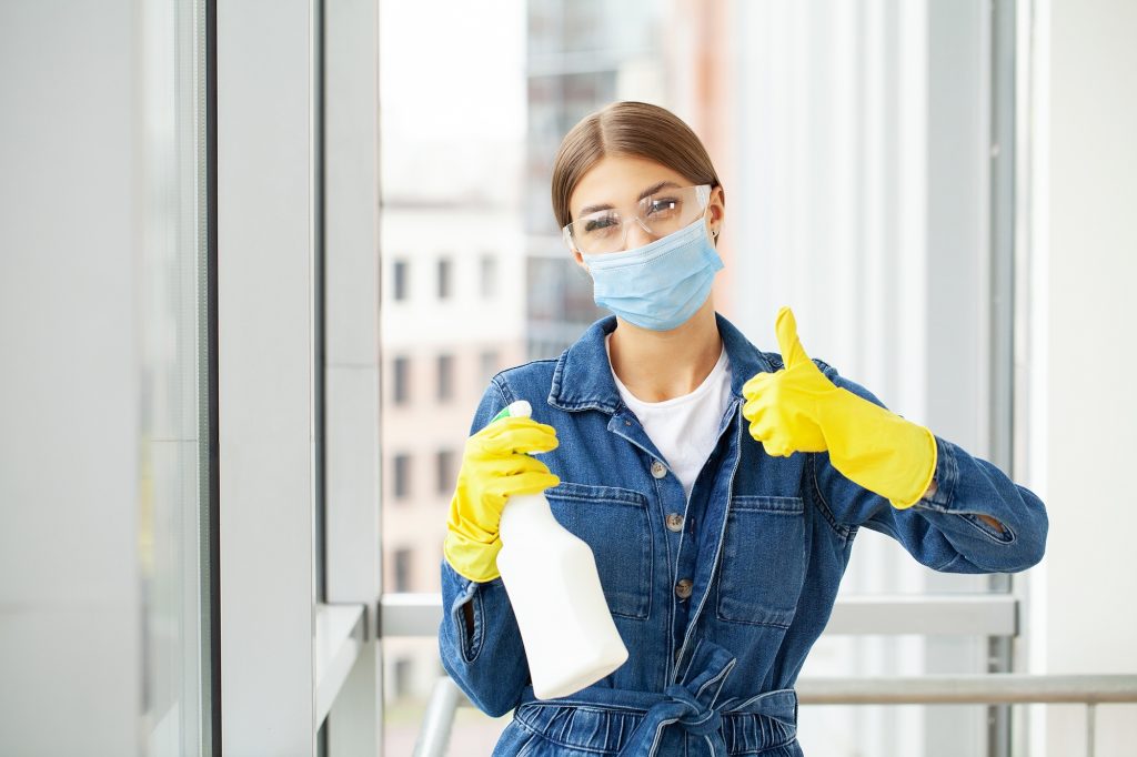 Woman professional cleaner in protective medical mask cleaning office